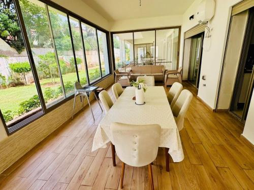 a dining room with a table and chairs and windows at Appartement Mer & Soleil à EL Mansoria in Pont Blondin