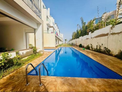 a swimming pool in front of a building at Appartement Mer & Soleil à EL Mansoria in Pont Blondin
