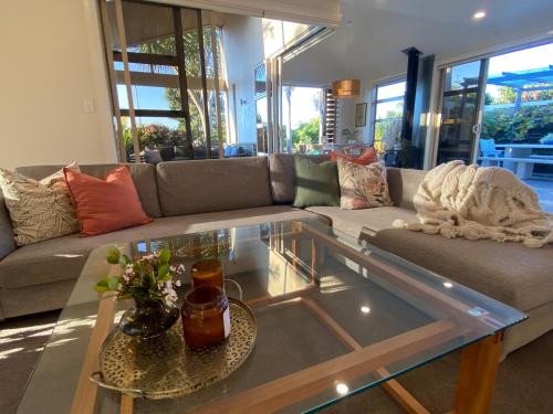 a living room with a couch and a glass table at Large Mt Maunganui Family Villa in Mount Maunganui