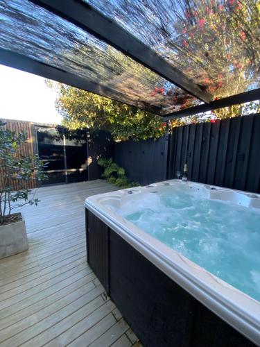 a jacuzzi tub in a backyard with a deck at Large Mt Maunganui Family Villa in Mount Maunganui