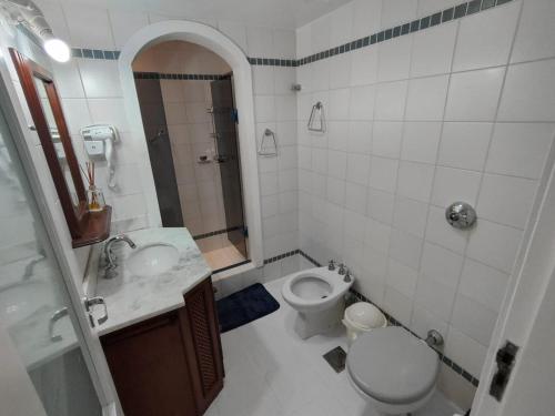 a white bathroom with a toilet and a sink at Mariechen 603, Perfeito, Central in Torres