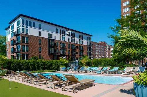 a swimming pool with lounge chairs and a building at 2BR w King Bed Pool Steps to Forest Park CWE in Tower Grove
