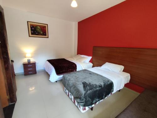 a bedroom with two beds and a red wall at Hotel Las Cañas in Baños