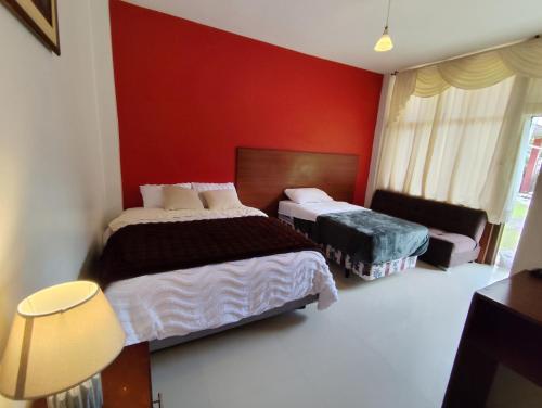 a bedroom with two beds and a red wall at Hotel Las Cañas in Baños