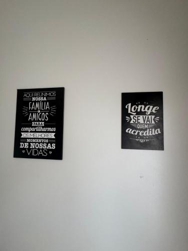 two signs hanging on a white wall at La Casa Lagoinha in Tigre