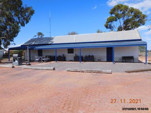 un gran edificio blanco con techo azul en Wirraminna Station Accommodation, 