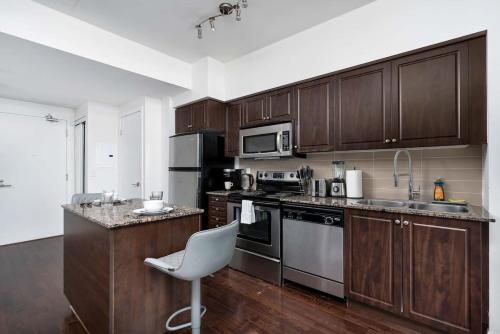 a kitchen with wooden cabinets and a white chair in it at Stylish Condo with Private Patio in Fortyork in Toronto