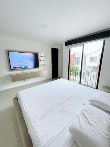 une chambre blanche avec un grand lit et une télévision à écran plat dans l'établissement Casa con piscina, zona BBQ y seguridad privada, à Amalia
