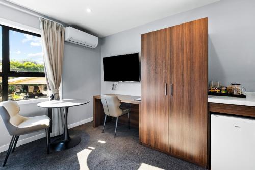 a hotel room with a desk and a large wooden cabinet at StarLand Stays in Auckland