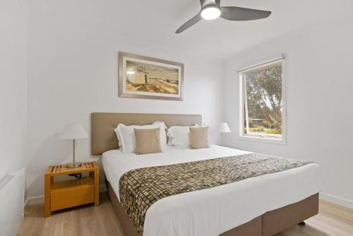 1 dormitorio blanco con 1 cama grande y ventilador de techo en Luxury Hills Villa Retreat Phillip Island Resort, en Cowes