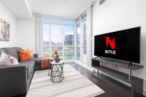 a living room with a tv and a large window at Downtown Escape Stylish Condo with City Views in Toronto
