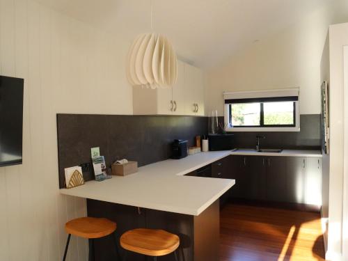 a kitchen with a white counter and two stools at Hideaway Falls - Staggys Cottage in Mapleton