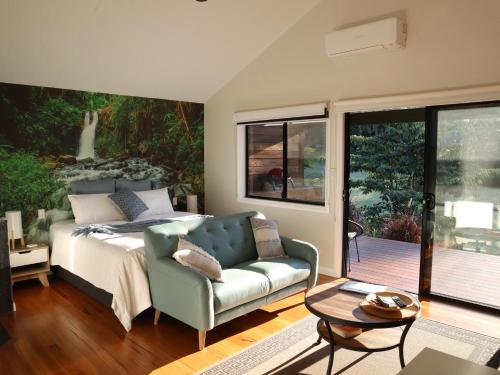 a bedroom with a bed and a couch and a table at Hideaway Falls - Staggys Cottage in Mapleton
