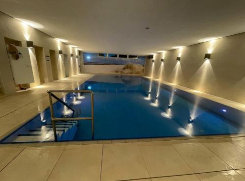 a large swimming pool with blue water in a building at Modern, Gemütlich, Strandnah in Cuxhaven