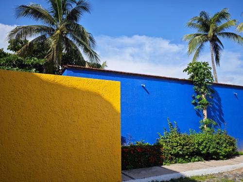 a blue and yellow wall with palm trees in the background at Hermoso y moderno departamento 2Hab, club de paya in Manzanillo