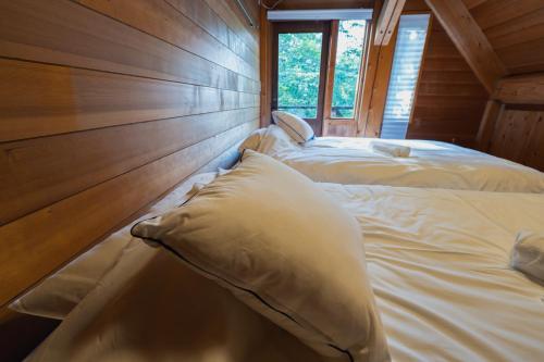 two twin beds in a room with a window at Hakuba Riverside Loghouse in Hakuba