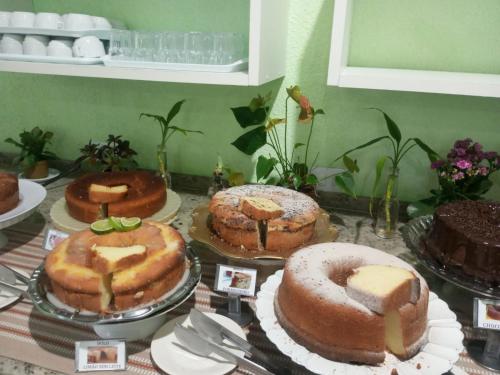 a table topped with cakes and other desserts on plates at Pousada Canto da Ilha in Ilha Comprida