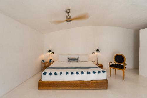 a white bedroom with a bed and a chair at NEST Baja in San José del Cabo