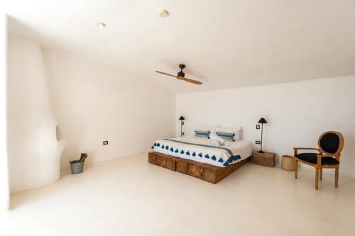 a white bedroom with a bed and a chair at NEST Baja in San José del Cabo