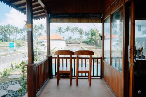 Dos sillas sentadas en el porche de una casa. en Uma Sunset Villa, en Ubud