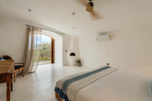 a white bedroom with a bed and a window at NEST Baja in San José del Cabo