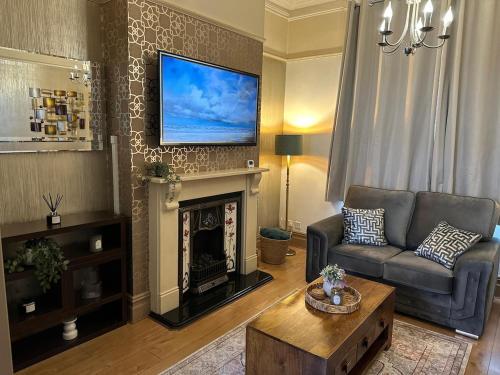 a living room with a couch and a tv above a fireplace at Comfy Stay Near City & Station in Preston