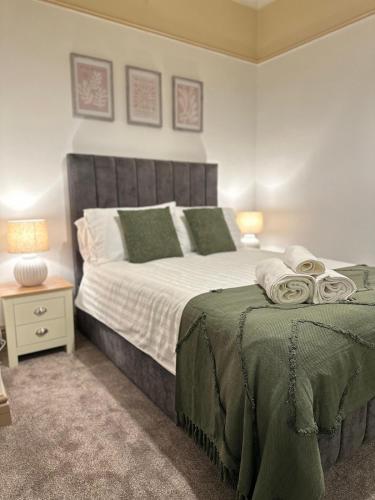 a bedroom with a large bed with green sheets and pillows at Comfy Stay Near City & Station in Preston