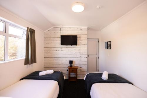 a bedroom with two beds and a tv on the wall at Haka House Taupo in Taupo