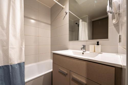 a white bathroom with a sink and a bath tub at Apartamento General Mackenna B&E in Santiago