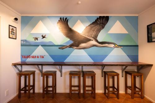 a mural of a bird flying over a bar with stools at Haka House Taupo in Taupo