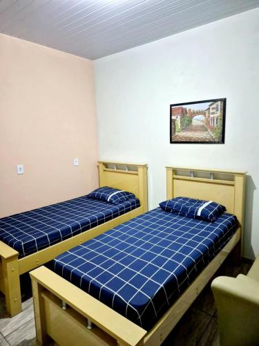 two beds in a room with blue sheets at Casa Miríades in Hortolândia