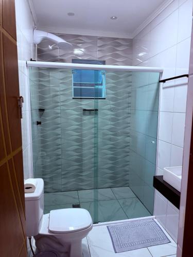 a bathroom with a glass shower with a toilet at Guaru Inn Hostel in Guarulhos