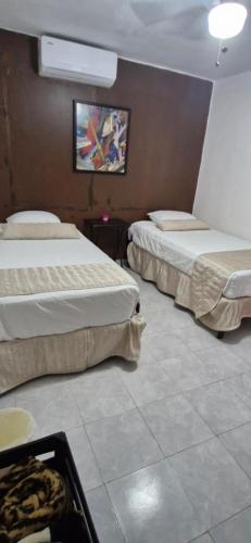 a hotel room with two beds and a tv at Alojamiento cómodo en Cancún in Cancún