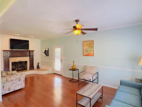 a living room with a ceiling fan and a fireplace at Sunlit Hideaway 3BR 2BA house pool in Little River