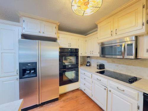 a kitchen with white cabinets and a stainless steel refrigerator at Sunlit Hideaway 3BR 2BA house pool in Little River