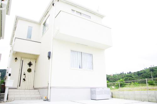 a white house with a white front door at 海まで徒歩3分の星降るやんばるテラスは1棟貸で古宇利島まで車で10分 in Nago