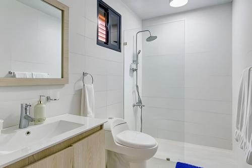 a white bathroom with a toilet and a shower at Caribbean Idyllic Vacation at Beachfront 1-BR Apt. in Juan Dolio