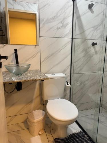 a bathroom with a toilet and a glass shower at Suíte Céu in Congonhas