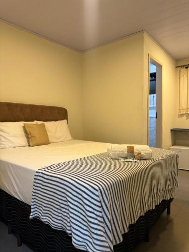 a bedroom with a large bed with a striped blanket at Suíte Céu in Congonhas