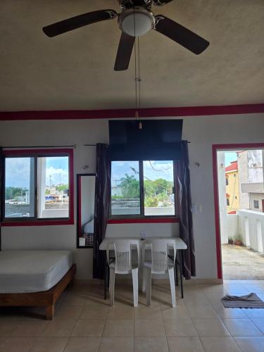 a bedroom with a table and two chairs and a ceiling fan at El Padrino in Akumal