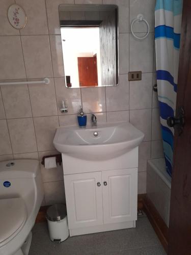 a bathroom with a sink and a toilet and a window at Hostal Möller in Villarrica