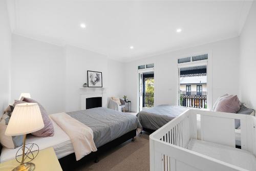 une chambre blanche avec deux lits et une fenêtre dans l'établissement Jam Home City Urban Oasis Darlinghurst Terrace, à Sydney