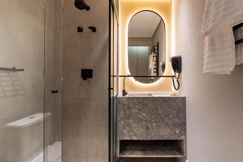 a bathroom with a shower and a sink and a mirror at Luxo na rua mais icônica do Itaim Bibi in Sao Paulo