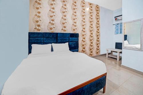 a bedroom with a large bed with a blue headboard at Hotel O Sai Anant in Bilāspur