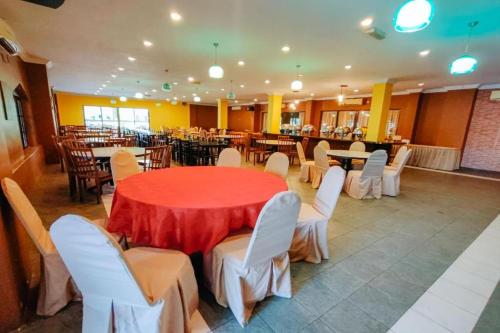 a dining room with a red table and white chairs at Virgo Batik Resort, Teluk Batik in Lumut