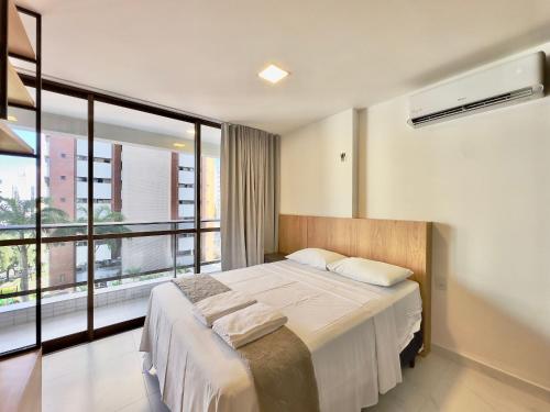 a bedroom with a large bed and a large window at JSmart - Carolina Sucupira in Fortaleza