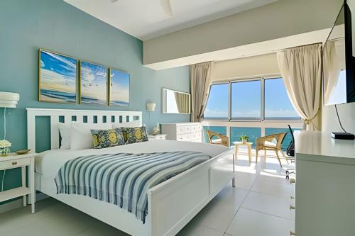1 dormitorio con paredes azules, 1 cama blanca y escritorio en Caribbean Ocean View, 2BDRM Beachfront Apartment, en Juan Dolio