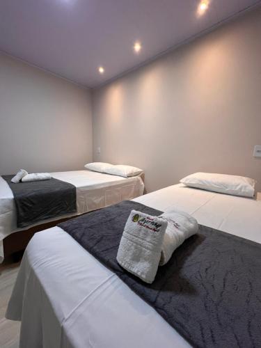 a room with two beds with white sheets at Hotel Matinha in Campinorte
