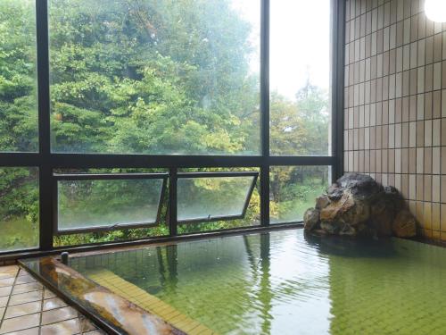a pool of water in a room with windows at せせらぎの宿吉野屋 in Nishiwaga