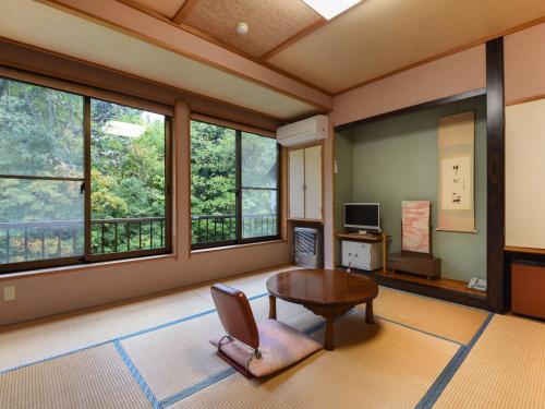a living room with a table and some windows at せせらぎの宿吉野屋 in Nishiwaga